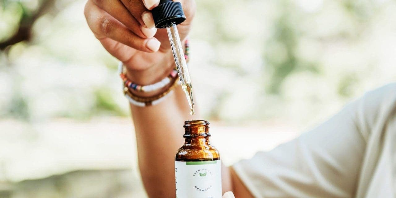 woman holding dropper of CBD oil