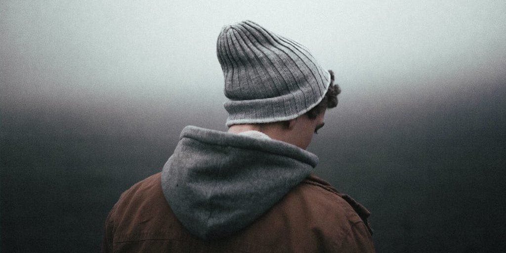 man on his back wearing jacket with hood and beanie hat